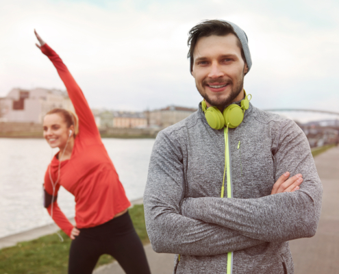 Een vrouw en een man die buiten aan het stretchen zijn als start om te gaan hardlopen omdat zij regelmatig te veel sporten