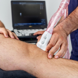 echografie Mannelijke patiënt krijgt echografie op zijn knie van de therapeut