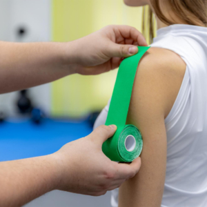 medical taping Medical taping wordt aangebracht op de schouder van een patiënt in de vorm van een groene tape